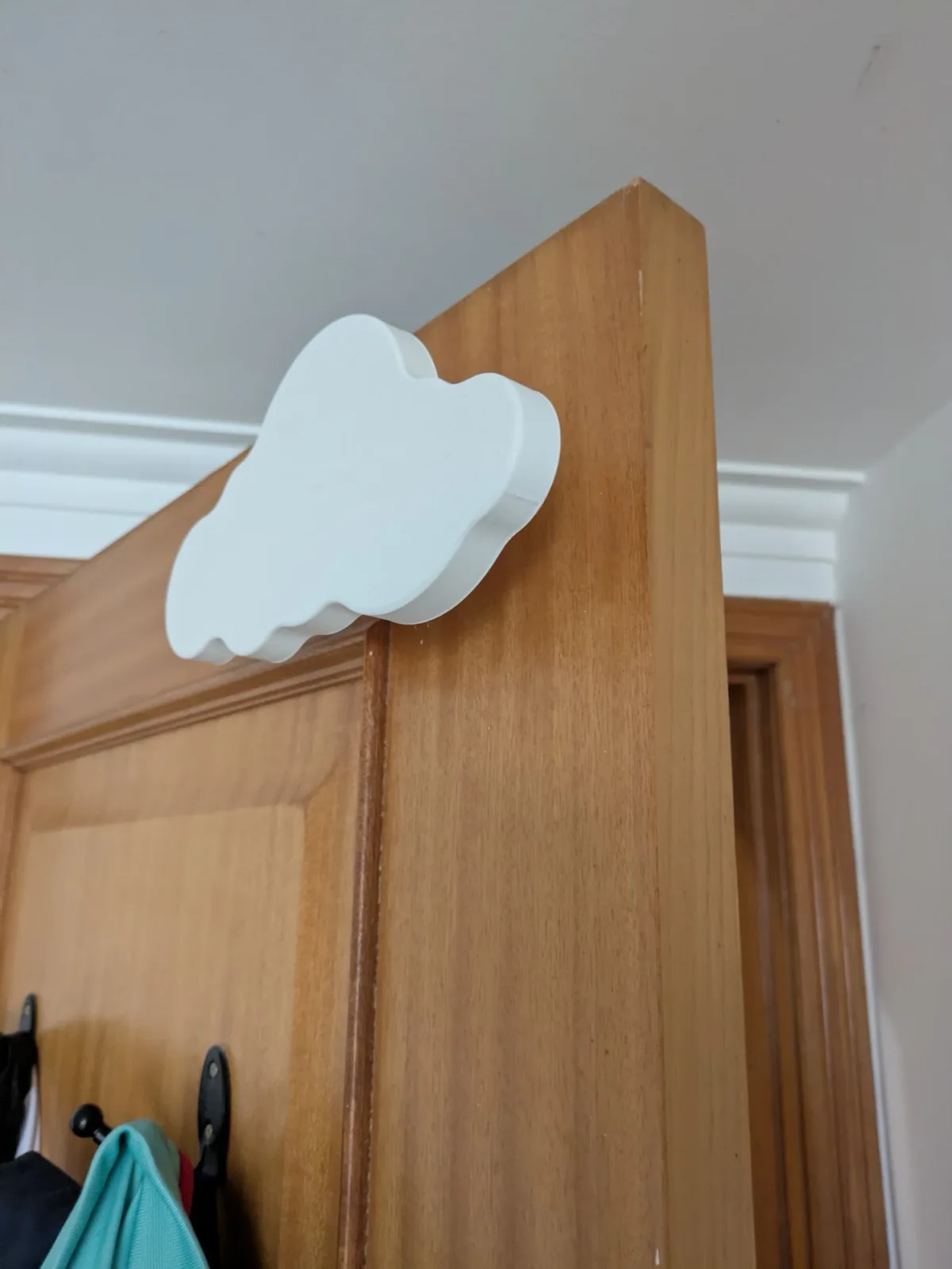 The printed cloud seen from the side, showing its layered profile sitting on the top edge of a door frame.