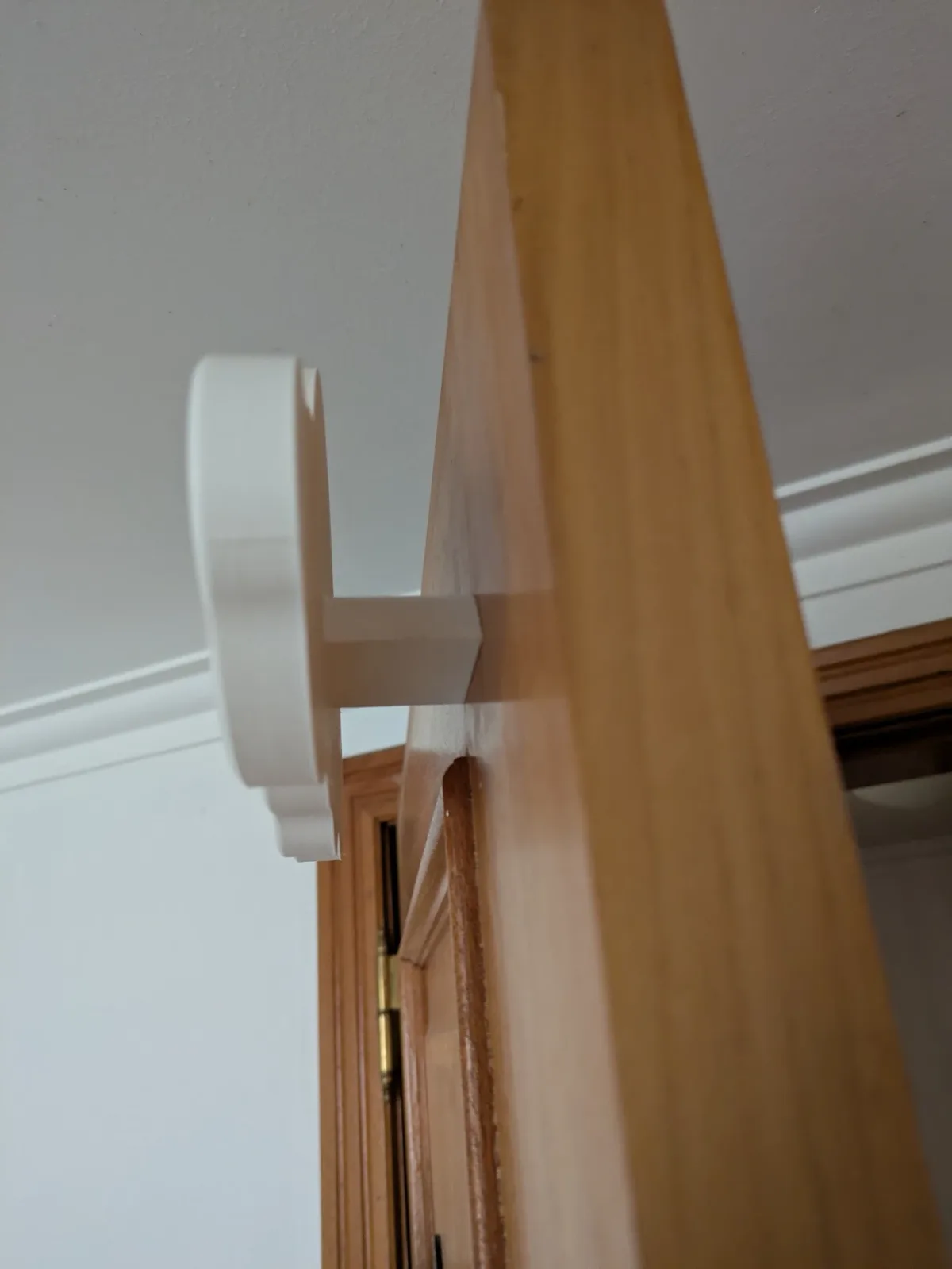 Edge-on view showing the hook arm of the cloud straddling the top edge of the door frame.